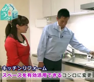 リフォーム担当者がキッチンのコンロを紹介している様子